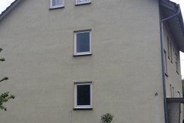Von nahmen fotographierte hellelfenbeinfarbene Trauf-Fassade mit vier Fenstern