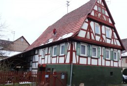 Fachwerkhaus mit rötlichem Fachwerk mit Fenstern in drei Stockwerken