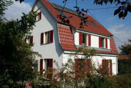 Wohngebäude mit mehrteiligem Dach mit weißer Fassade und rötlichen Ziegeln