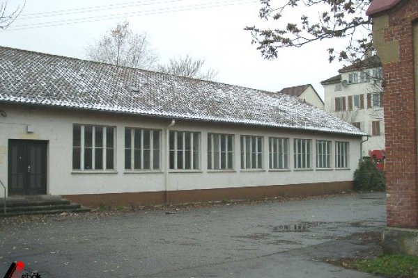 Langes, niedriges Gebäude mit bräunlichem, leicht schneebedecktem Dach