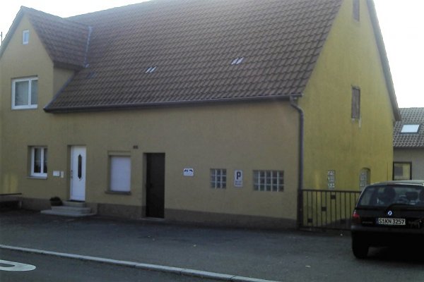 Von Traufseite aus fotographiertes längliches Gebäude mit gelblicher Fassade
